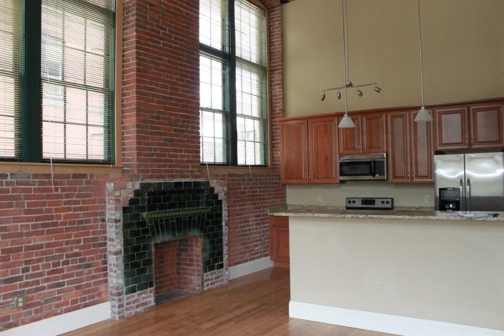 64 Beacon Street, Unit C105 Worcester, MA 01608 - Photo 9 of 23 a kitchen with stainless steel appliances granite countertop a stove a sink and a microwave
