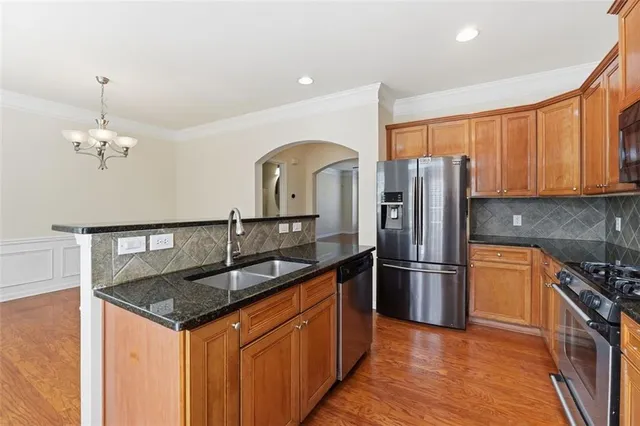 a kitchen with stainless steel appliances granite countertop a sink refrigerator and cabinets