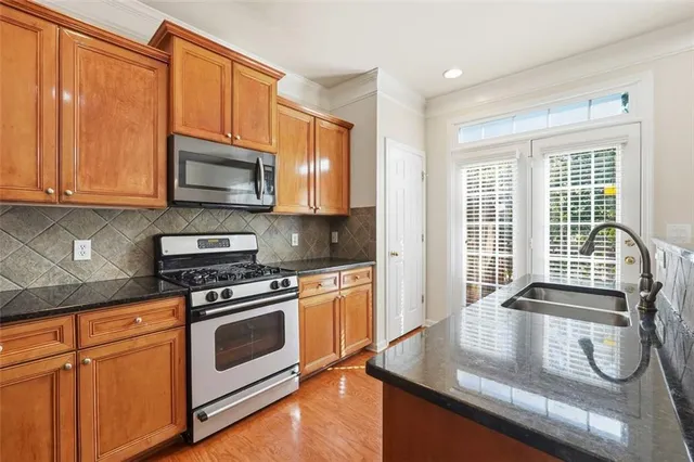 a kitchen with stainless steel appliances granite countertop a stove a sink and a microwave