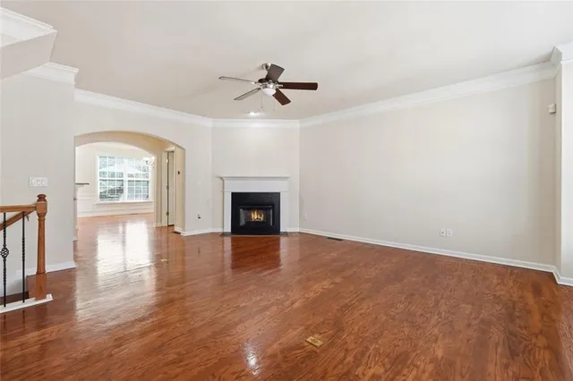 an empty room with wooden floor fireplace and windows