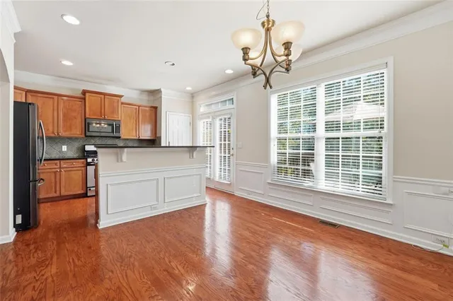 a kitchen with stainless steel appliances granite countertop a stove top oven a refrigerator a sink and dishwasher with wooden floor