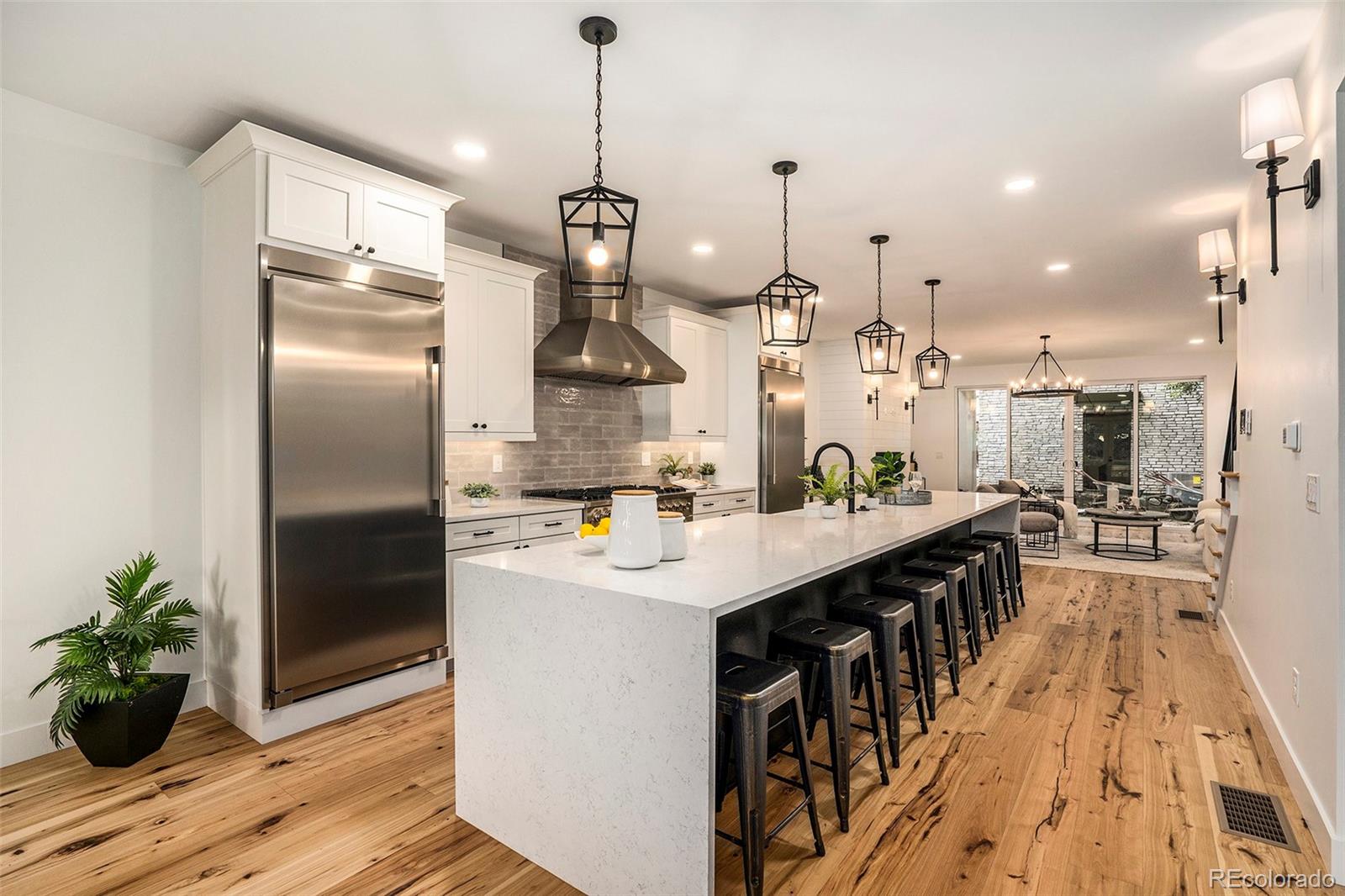 3271 Perry Street Denver, CO 80212 - Photo 6 of 34 a kitchen with stainless steel appliances kitchen island a refrigerator a stove a sink and a dining table with wooden floor