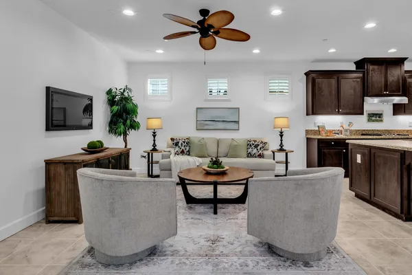 a living room with furniture kitchen view and a chandelier