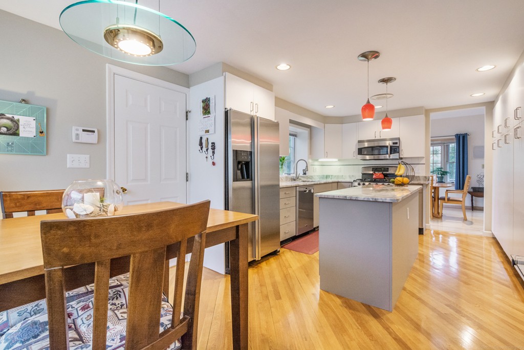 9 Powder Hill Way, Unit 9 Westborough, MA 01581 - Photo 12 of 30 a kitchen with stainless steel appliances granite countertop a refrigerator a stove top oven and a dining table with wooden floor