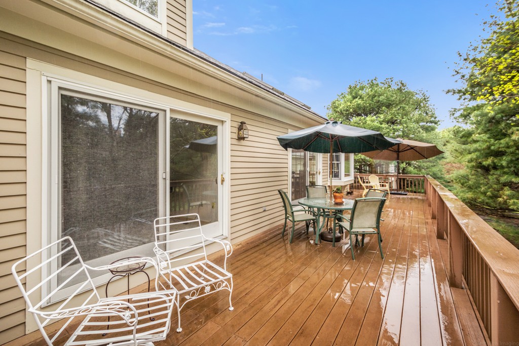9 Powder Hill Way, Unit 9 Westborough, MA 01581 - Photo 27 of 30 a view of a patio with a table and chairs under an umbrella with wooden floor