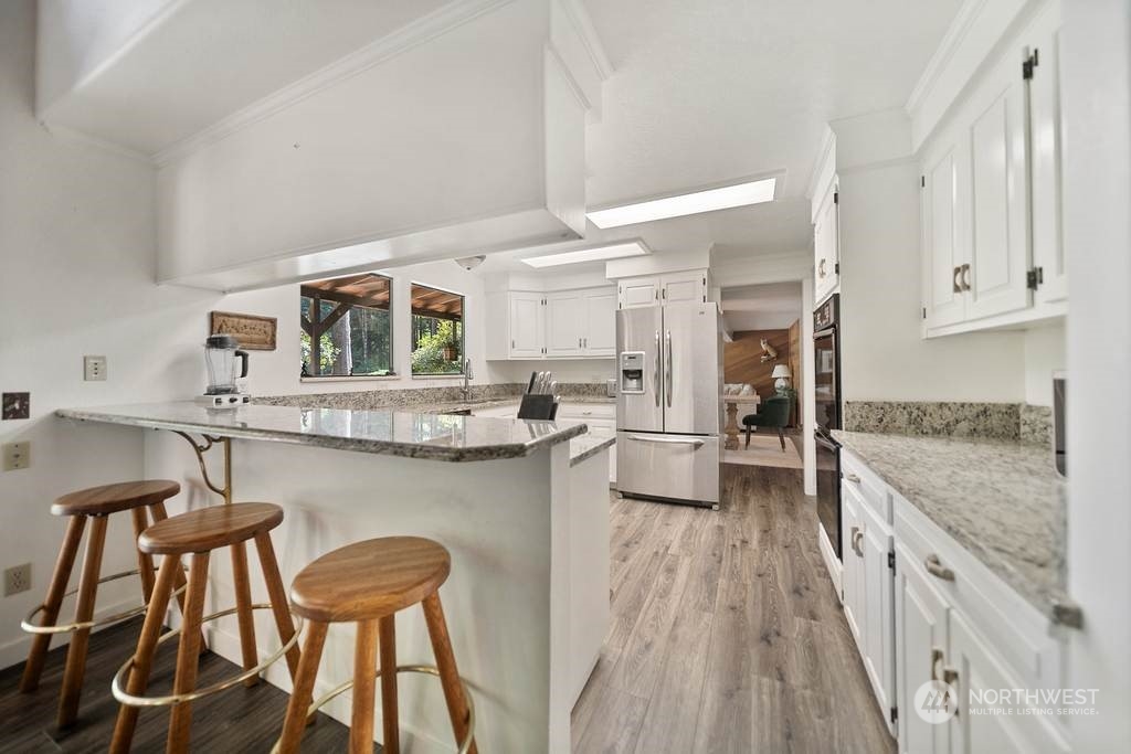 1171 Big Pine Way Forks, WA 98331 - Photo 12 of 40 a kitchen with stainless steel appliances granite countertop a stove top oven a sink a dining table and chairs with wooden floor
