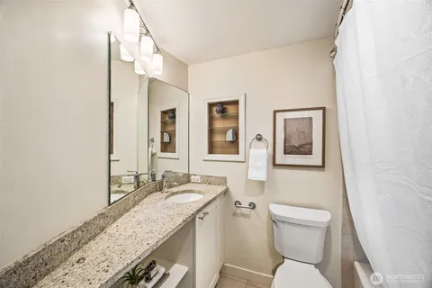 a bathroom with a granite countertop sink a toilet and a mirror