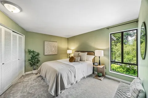 a bedroom with a bed lamp and a large window