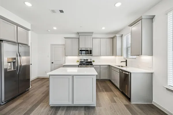a kitchen with a sink stainless steel appliances and wooden floor