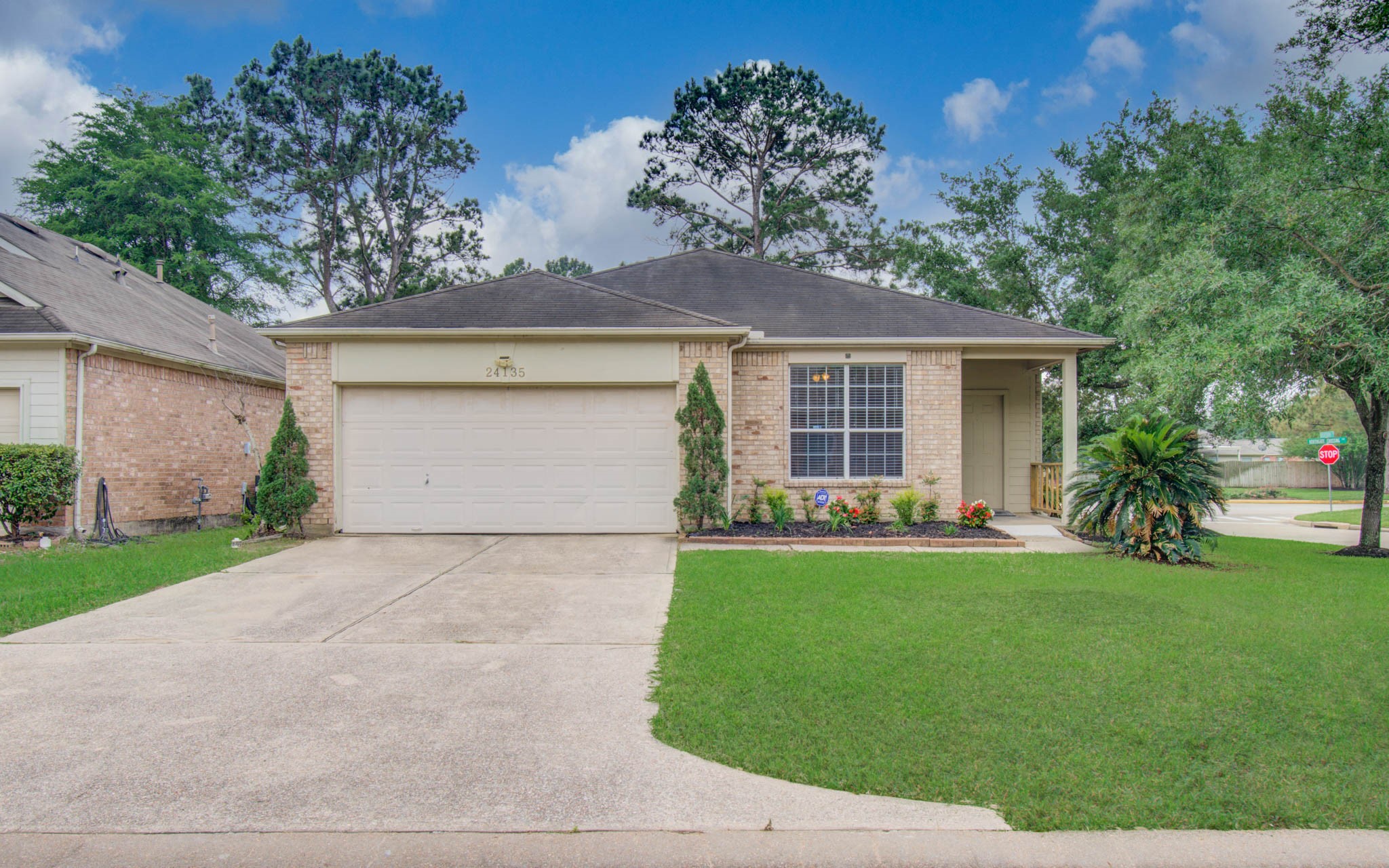 Front exterior view of the home with two-car garage, mature trees, and landscaped front yard