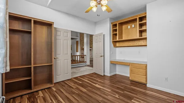 a view of empty room with wooden floor and fan
