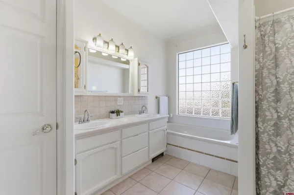 a bathroom with a double vanity sink mirror and bathtub