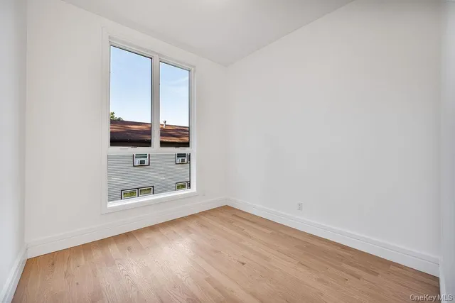 an empty room with wooden floor cabinet and windows