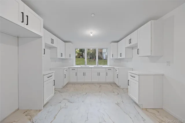 a kitchen with white cabinets and wooden floors