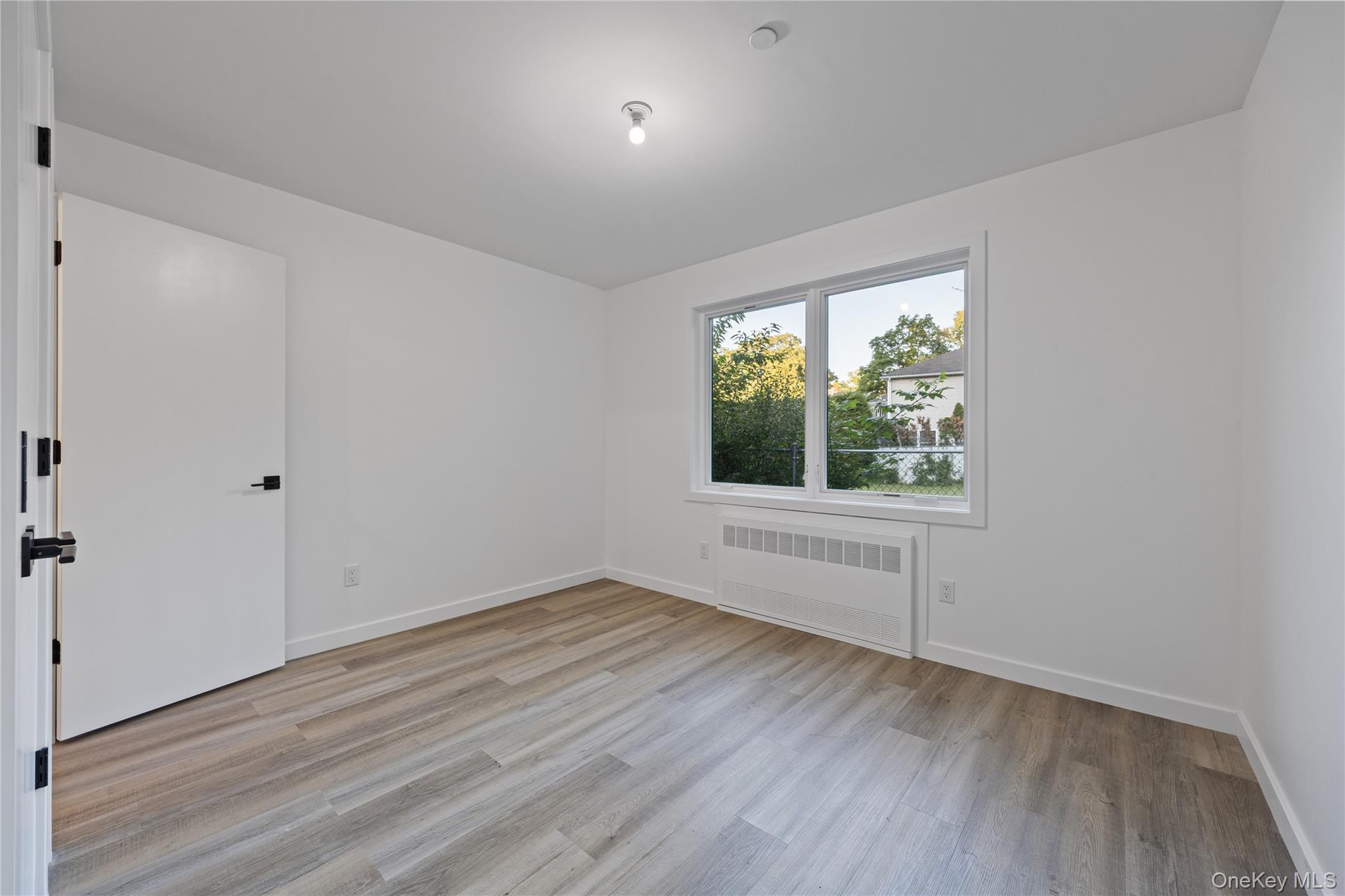 40 Singer Avenue, Unit 201 Spring Valley, NY 10977 - Photo 47 of 50 a view of an empty room with wooden floor and a window