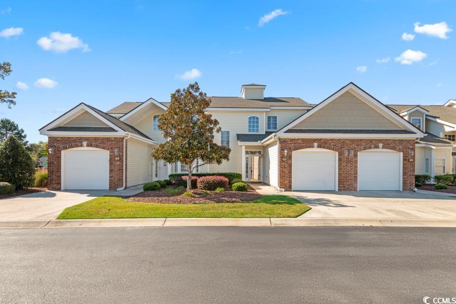 View of front of property featuring a garage, concrete driveway, and brick siding