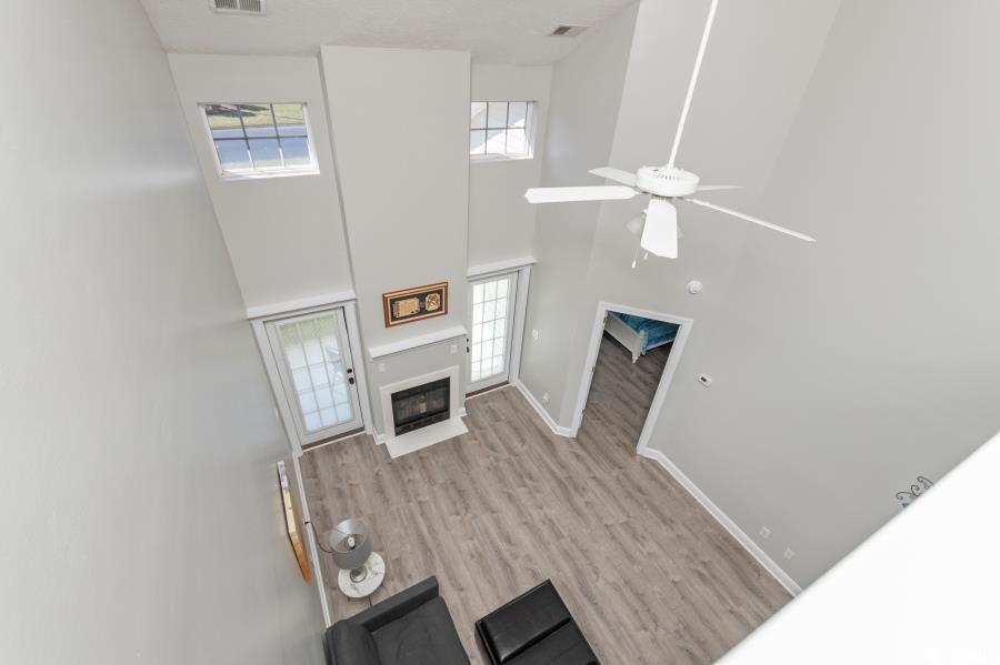 110 Cart Crossing Drive, Unit 102 Conway, SC 29526 - Photo 13 of 39 Unfurnished living room with a high ceiling, a fireplace with flush hearth, light wood-type flooring, and ceiling fan