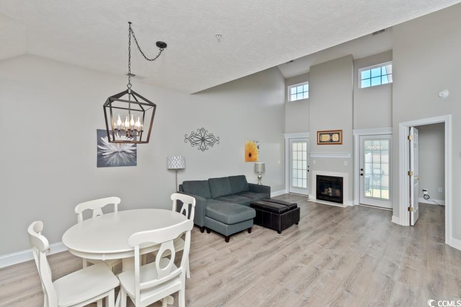 110 Cart Crossing Drive, Unit 102 Conway, SC 29526 - Photo 10 of 39 Dining room featuring light wood finished floors, a high ceiling, plenty of natural light, a fireplace, and a textured ceiling