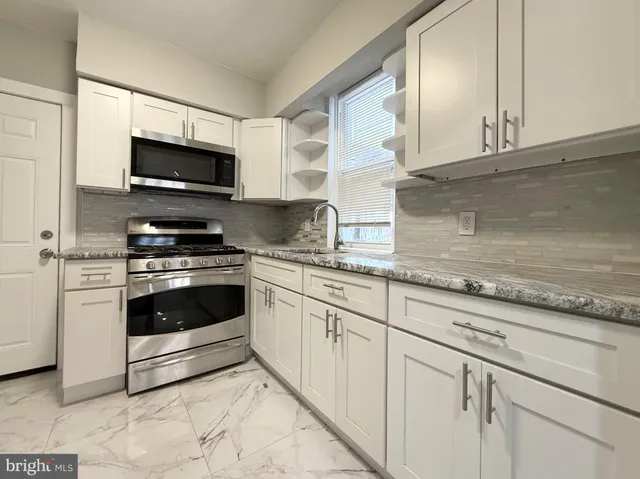 a kitchen with granite countertop white cabinets white stainless steel appliances and a sink