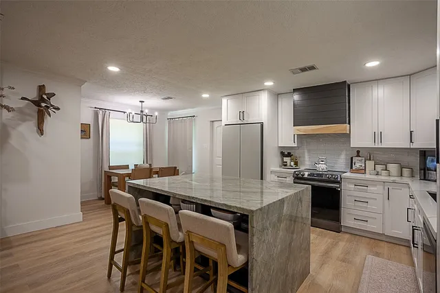 a kitchen with stainless steel appliances granite countertop a kitchen island hardwood floor sink stove and refrigerator