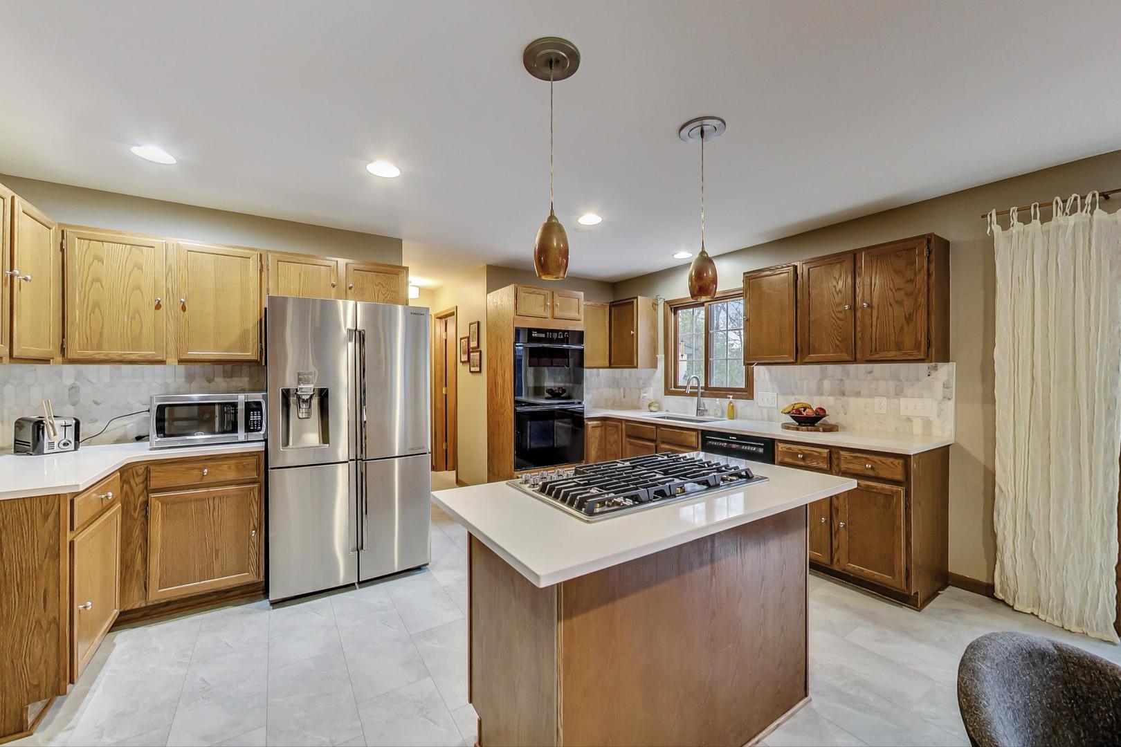 2185 Maplewood Drive Gurnee, IL 60031 - Photo 11 of 65 a kitchen with a refrigerator a stove top oven a sink dishwasher and white cabinets with wooden floor