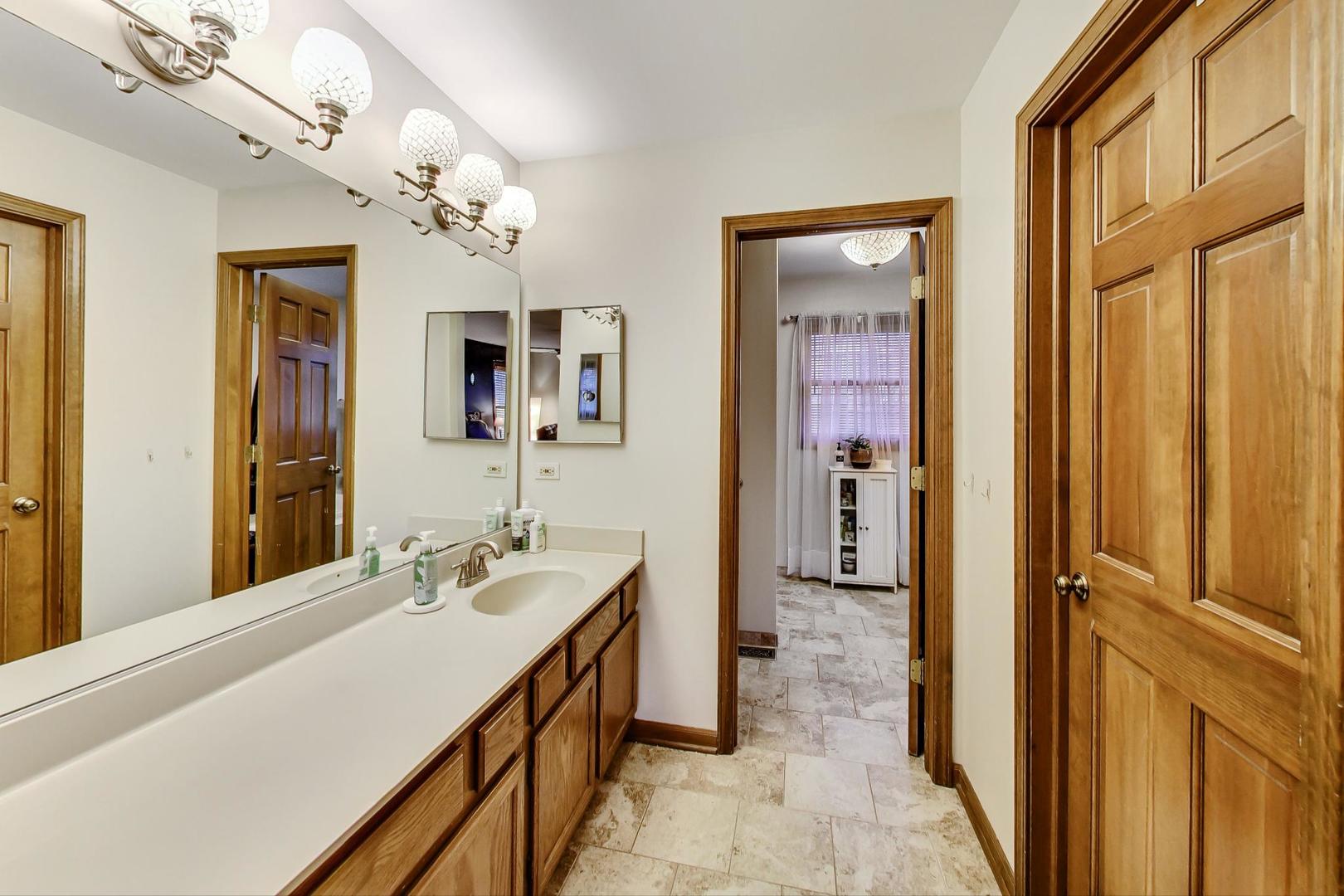 2185 Maplewood Drive Gurnee, IL 60031 - Photo 26 of 65 a en suite bathroom with a sink a mirror and a shower