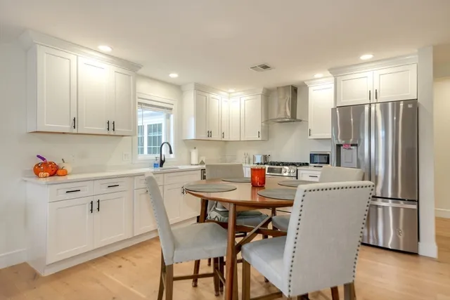a kitchen with stainless steel appliances granite countertop a table chairs sink refrigerator and cabinets
