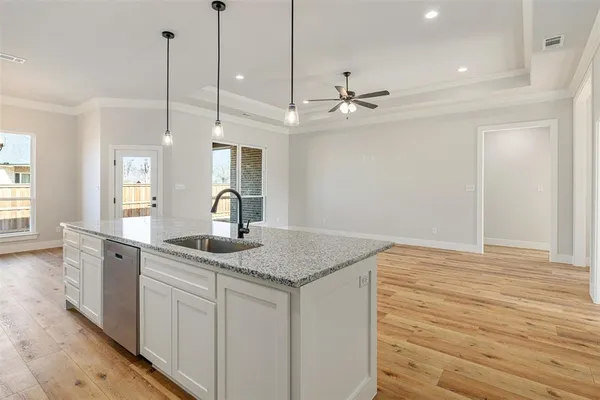 a kitchen with a sink dishwasher and wooden floor