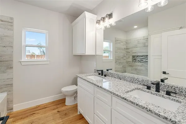 a bathroom with a granite countertop sink a toilet and a mirror