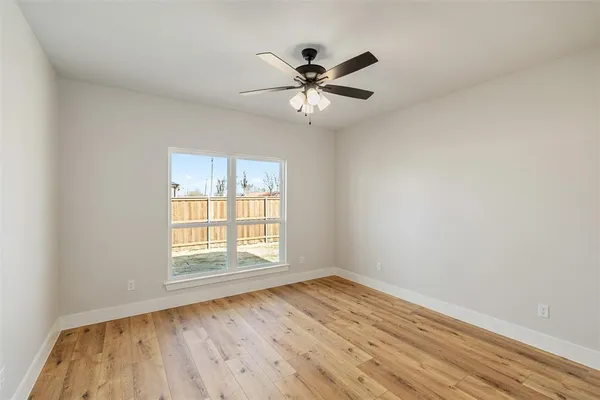 an empty room with wooden floor fan and windows