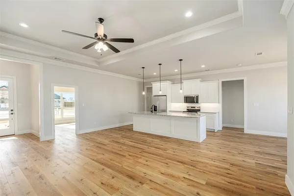 a large kitchen with kitchen island a stove a sink dishwasher a refrigerator and white cabinets with wooden floor