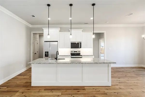 a view of a kitchen with kitchen island a sink stainless steel appliances and cabinets