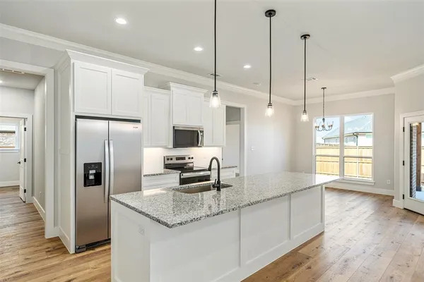 a kitchen with stainless steel appliances granite countertop a refrigerator a sink and a wooden floor