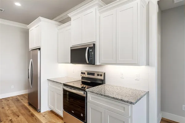 a kitchen with white cabinets and stainless steel appliances