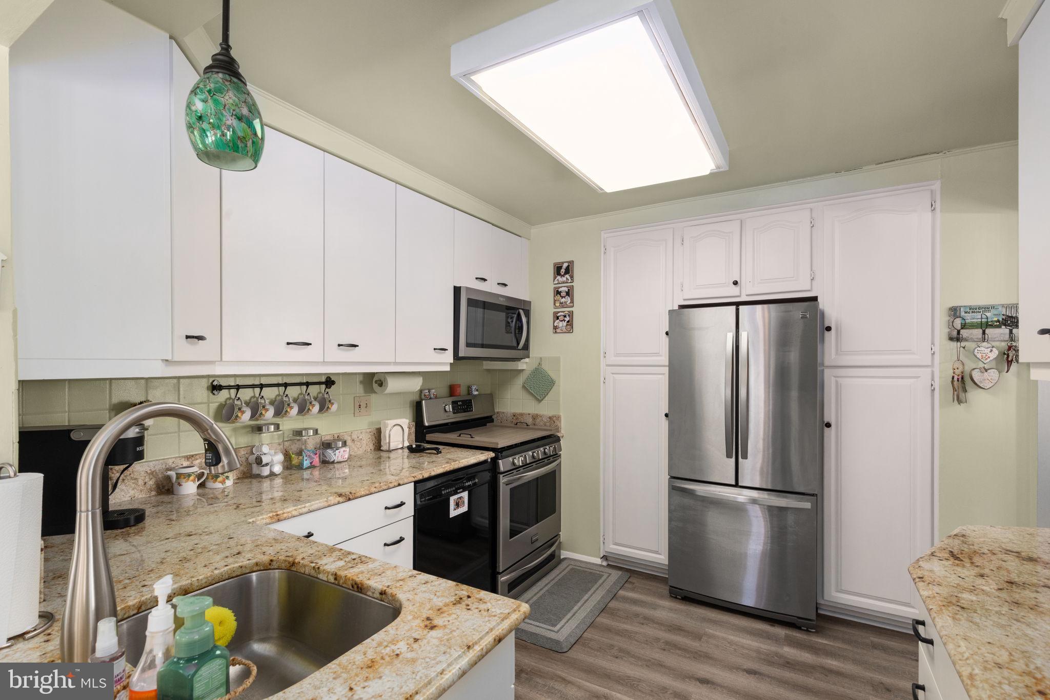 3409 Acton Road Parkville, MD 21234 - Photo 9 of 27 a kitchen with stainless steel appliances granite countertop a refrigerator a sink a stove and a wooden floors