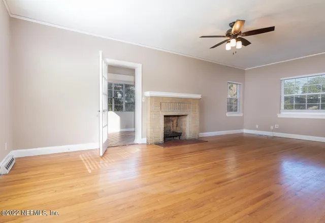 an empty room with wooden floor cabinet and windows