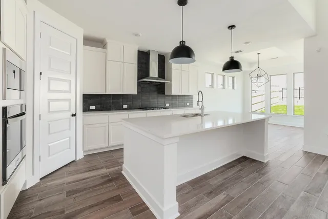 a kitchen with stainless steel appliances granite countertop a sink a stove and a wooden floors