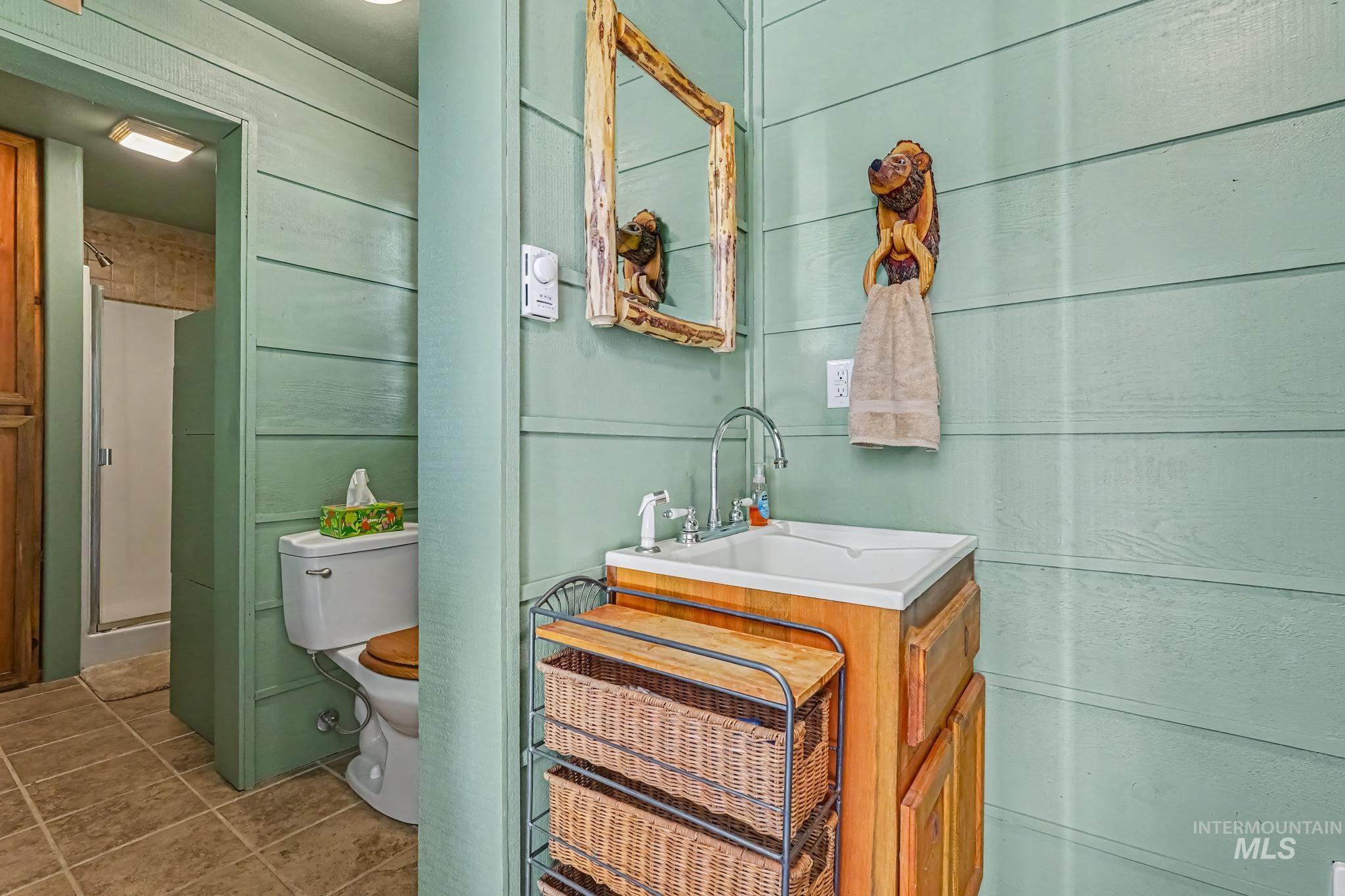 106 Wilderness Lake Road Cascade, ID 83611 - Photo 20 of 35 Light green horizontal wood paneling, tiled flooring, and a shower with a sliding glass door