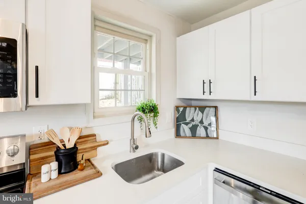 a kitchen with stainless steel appliances granite countertop a sink a stove and white cabinets with wooden floor