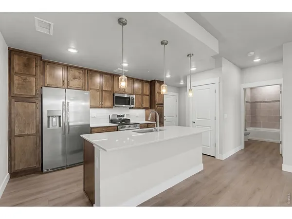 a kitchen with stainless steel appliances granite countertop a refrigerator a sink a stove and a refrigerator