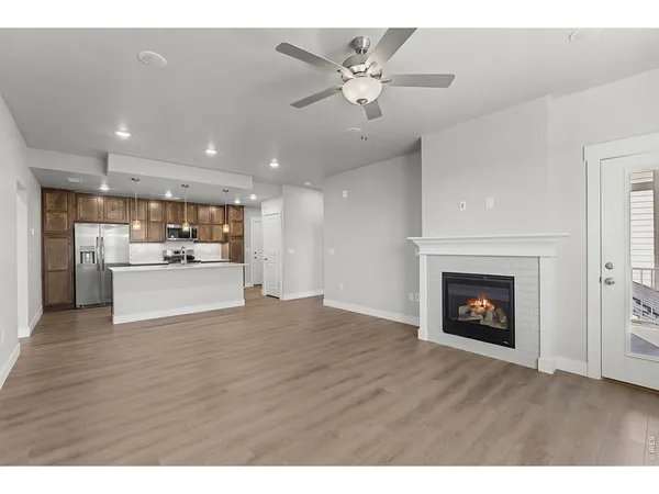 a view of an empty room and kitchen with fireplace wooden floor