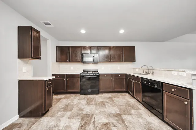 a large kitchen with granite countertop a sink and cabinets