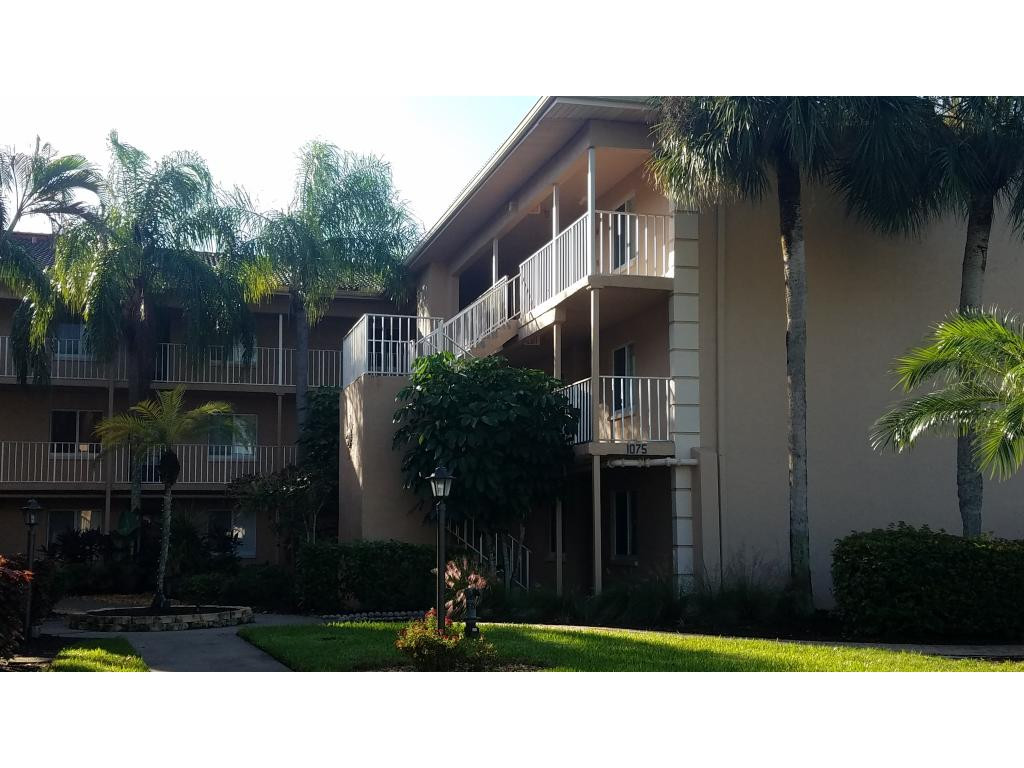 1075 Foxfire Lane, Unit 103 Naples, FL 34104 - Photo 1 of 1 a black and white building with trees in the background