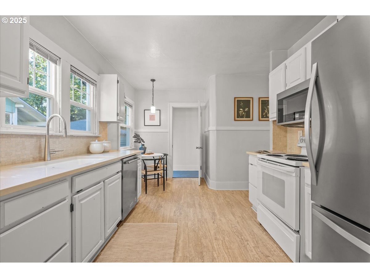 3448 Southeast Sherman Street Portland, OR 97214 - Photo 15 of 40 a kitchen with stainless steel appliances granite countertop a refrigerator a sink dishwasher a stove and white countertops with wooden floor