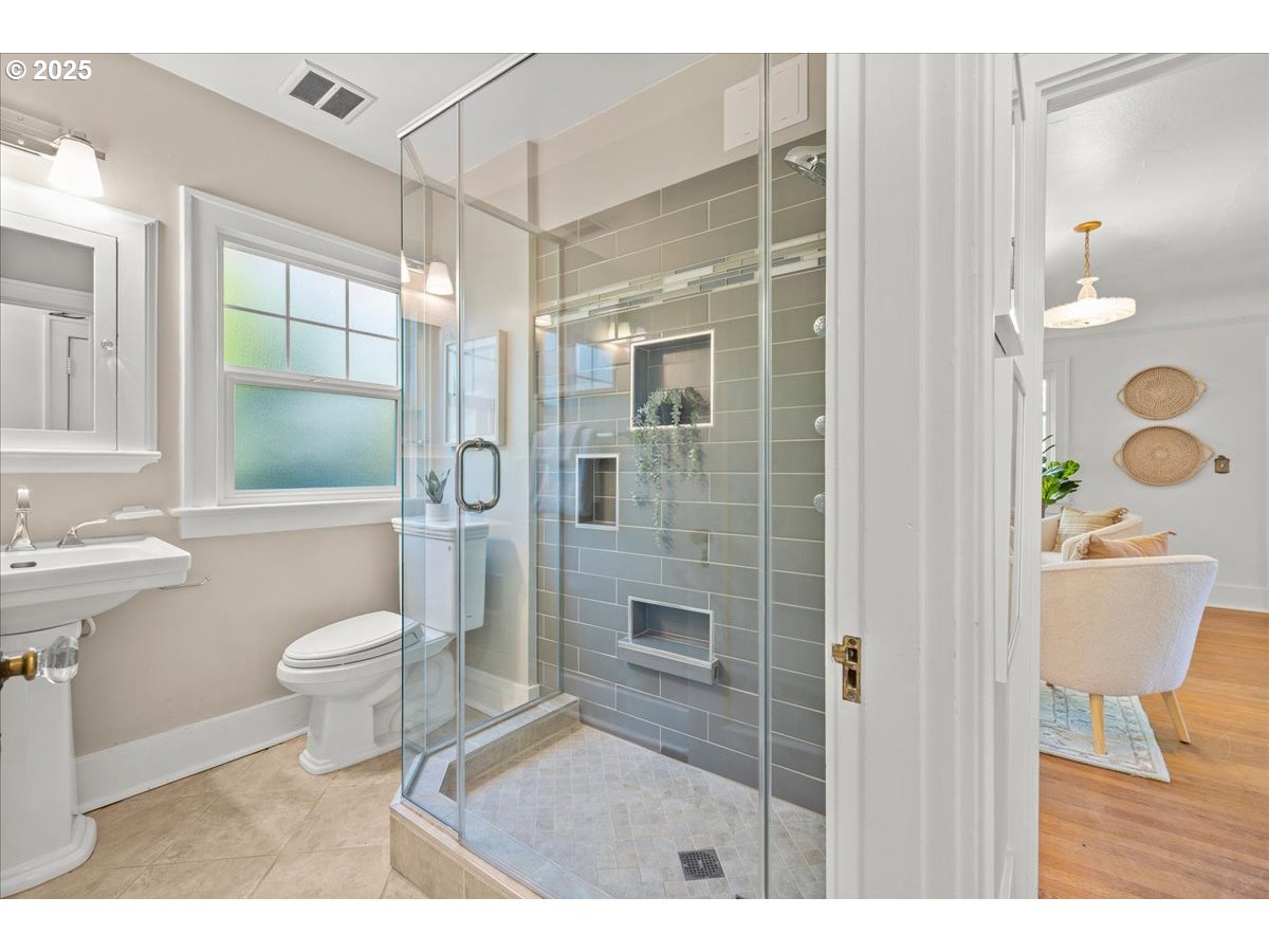 3448 Southeast Sherman Street Portland, OR 97214 - Photo 23 of 40 a bathroom with a granite countertop sink a toilet a mirror and shower