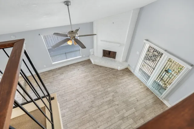 a view of an empty room with wooden floor fireplace and a window