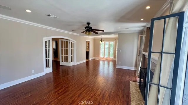 an empty room with wooden floor and a ceiling fan