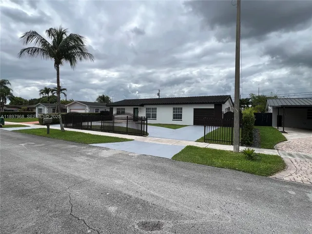 a view of a house with a yard and palm trees