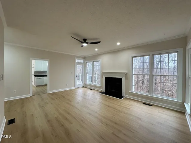 an empty room with wooden floor fireplace and windows