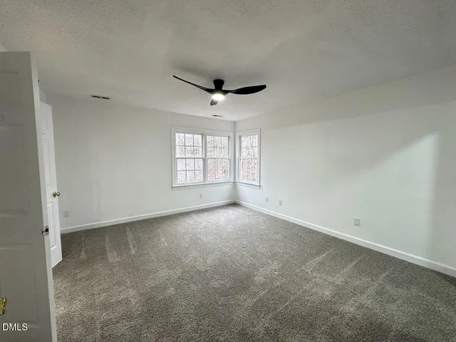 an empty room with windows and ceiling fan